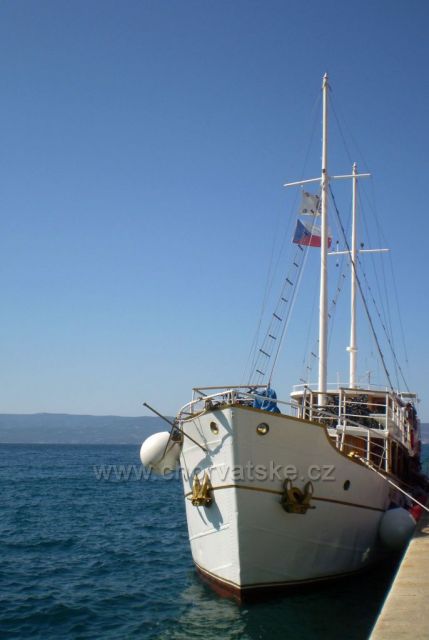 Loď s českou vlajkou na Jadranu naložená bicykly pro turistiku českých nadšenců v přístavu