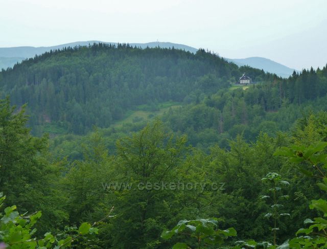 Pohled k horské chatě Hrádek pod stejnojmenným vrchem z lesní silničky do Návsí
