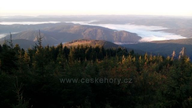 Výhled z Lysé hory na vrch Zimný a udolí říčky Mohelnice v ranní mlze.