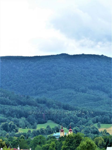 Lázně Libverda - pohled z okraje lázeňského parku na poutní kostel Navštívení Panny Marie v Hejnicích. Na obzoru se rýsují Ořešník a Holubník.